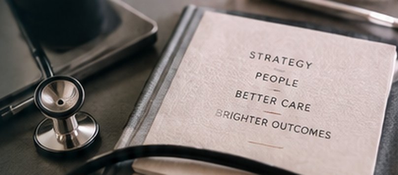 A stethoscope resting beside a book titled Strategy, People, Better Care, Brighter Outcomes